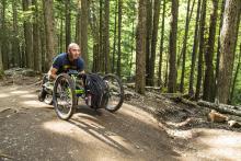 man in a racing wheelchair in the woods